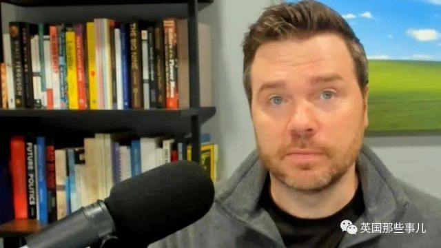 Man speaking into a microphone in front of bookshelves