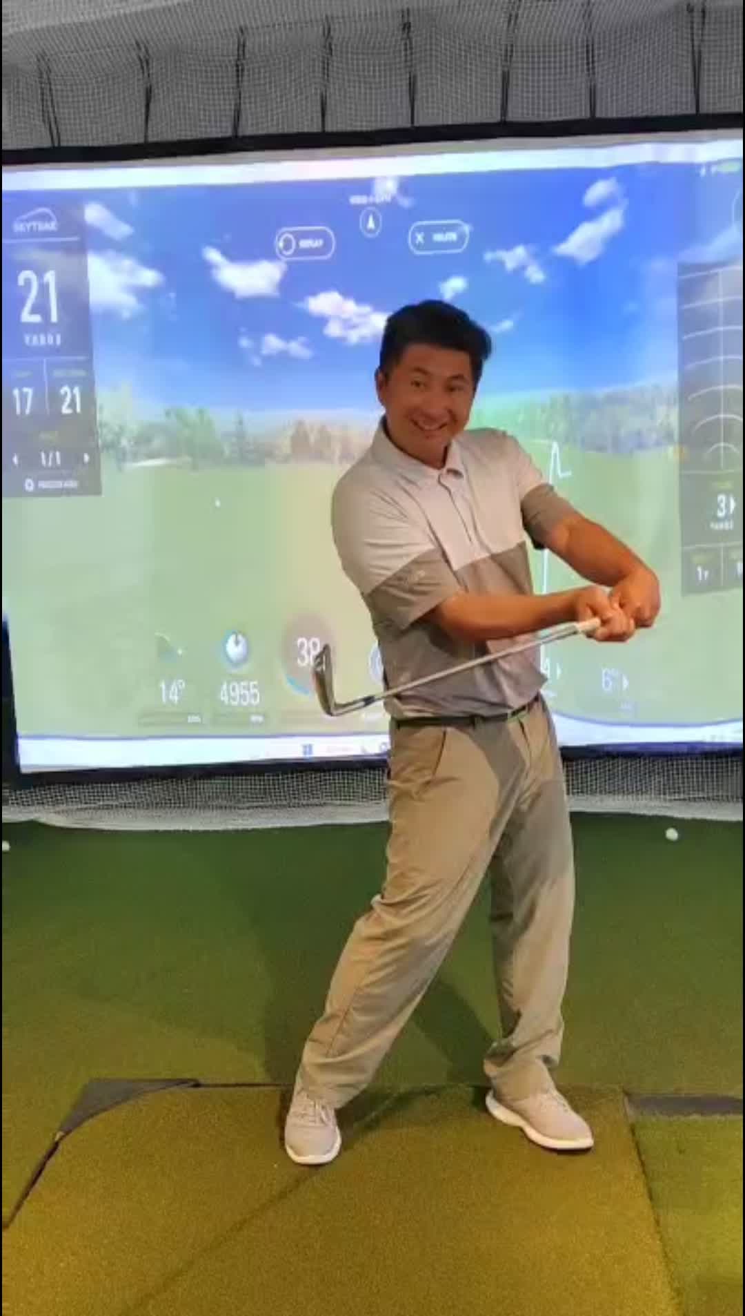 Golfer demonstrating a swing position indoors in front of a screen