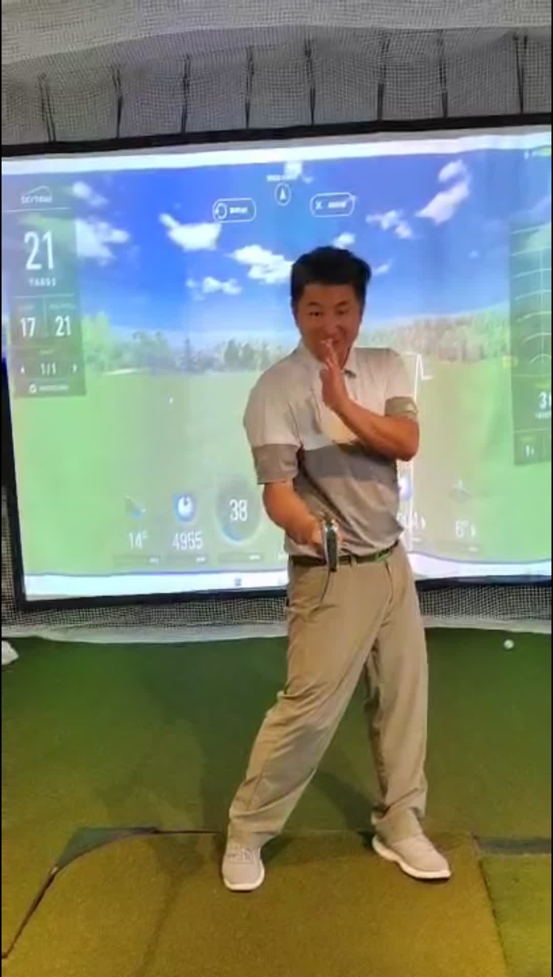 Golfer demonstrating a swing position indoors in front of a screen