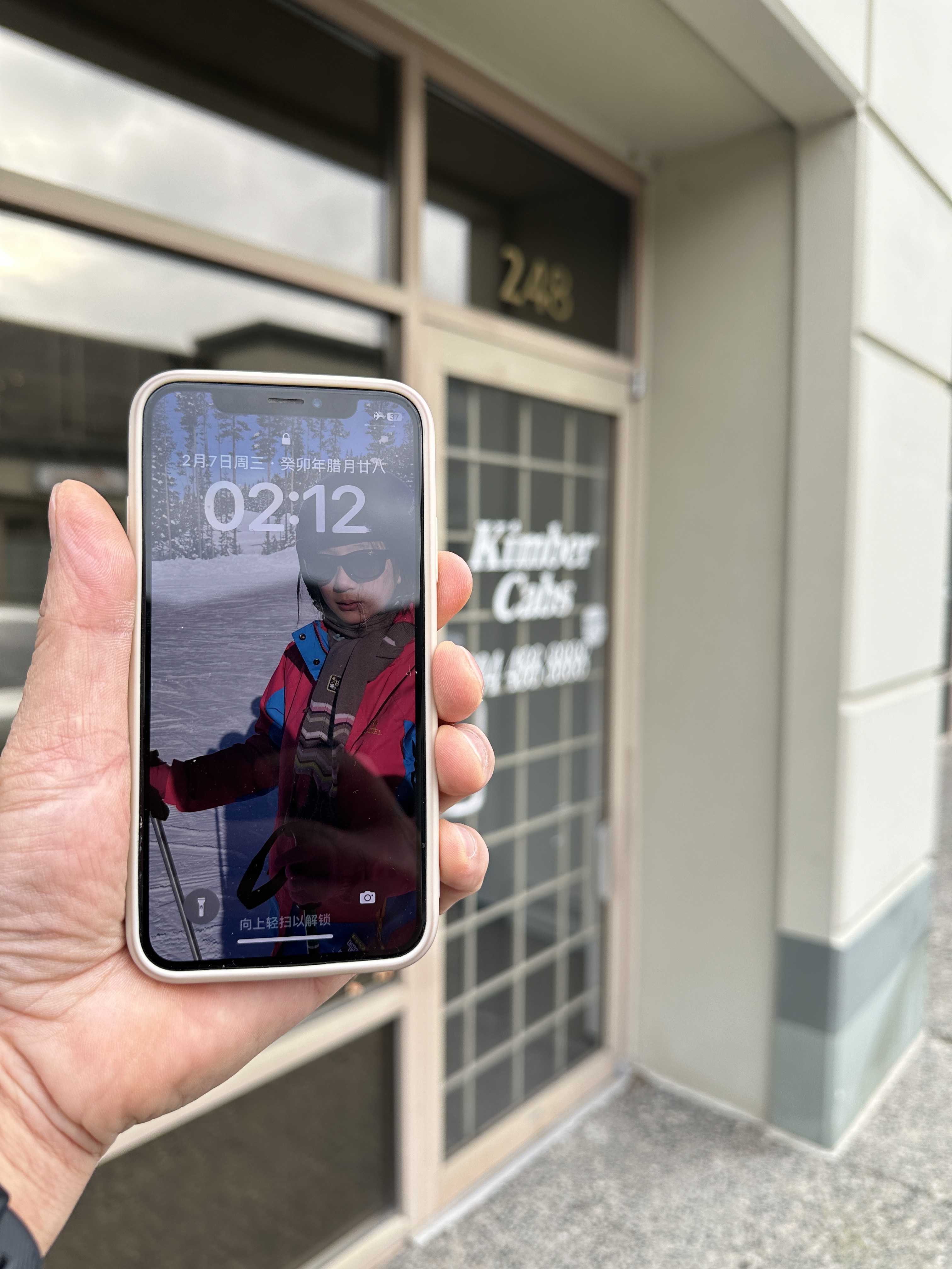 A hand holding an iPhone outside a building entrance
