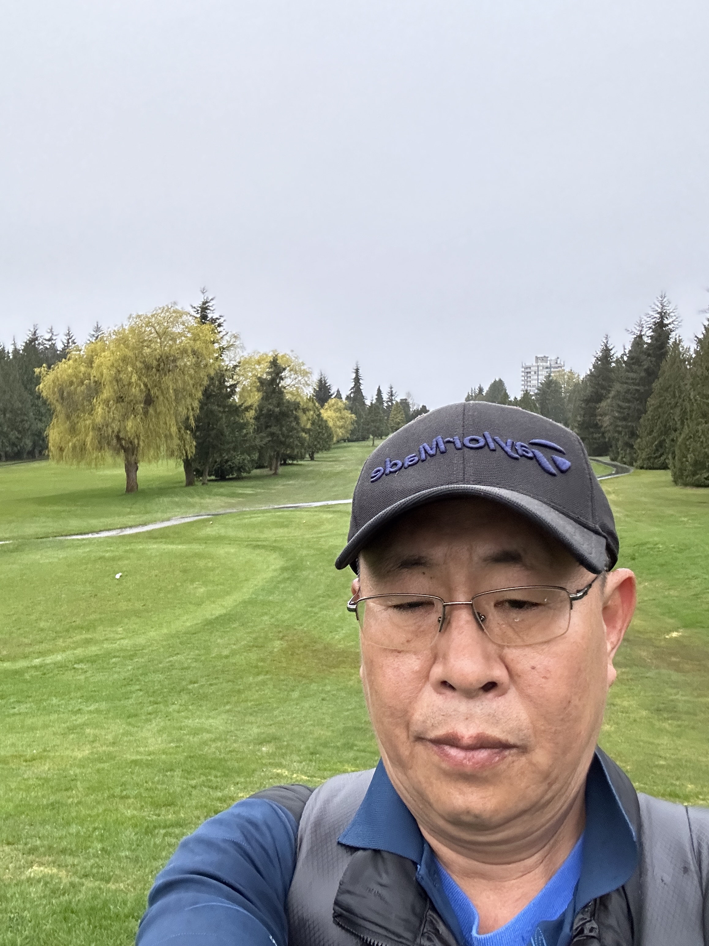 Hauwson wearing a golf cap beside a fairway and trees