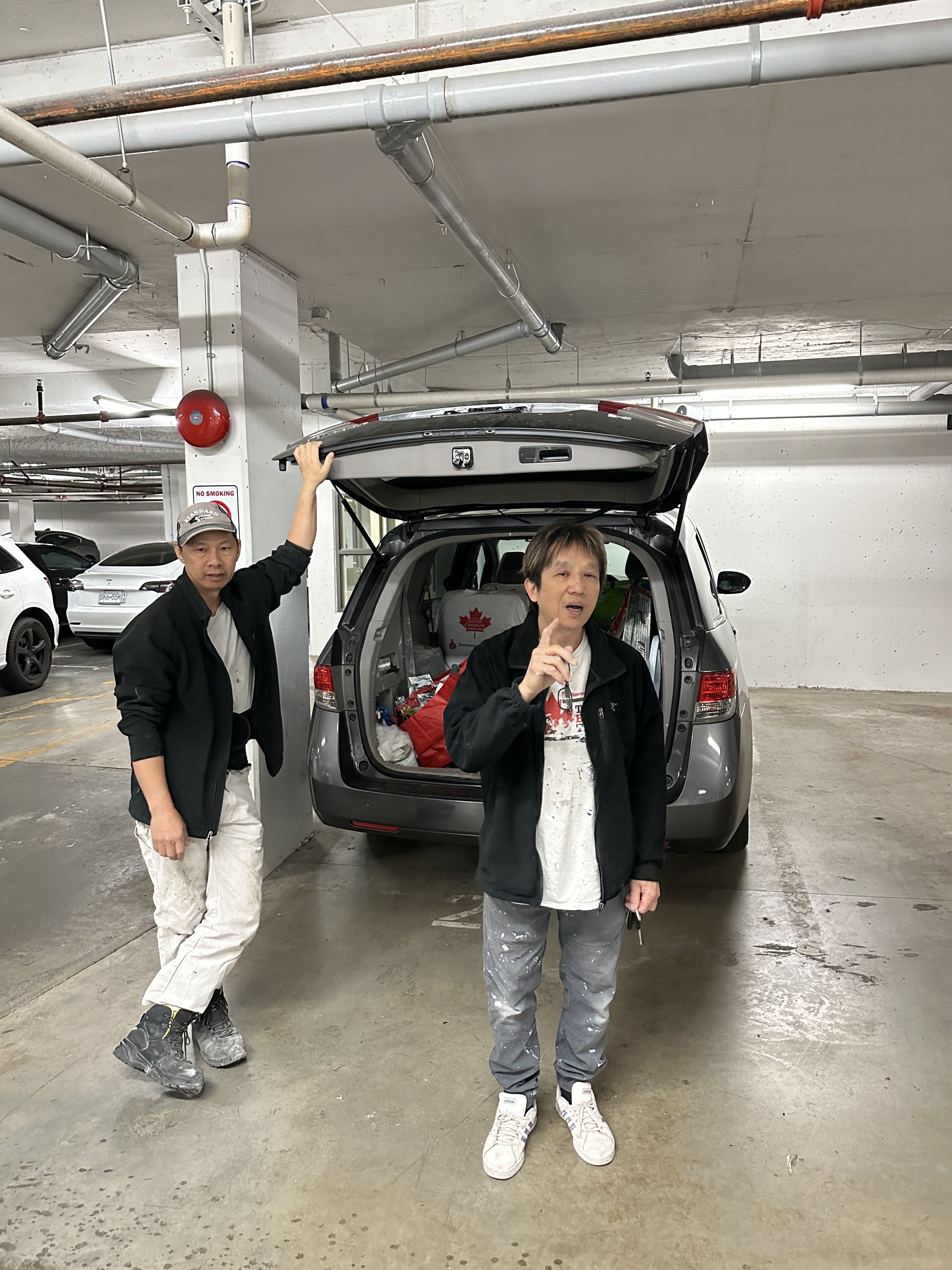 Two men beside an open car trunk in a parking garage