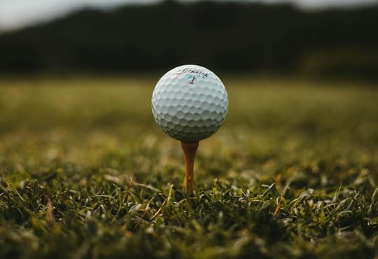 Golf ball on a tee against green turf.